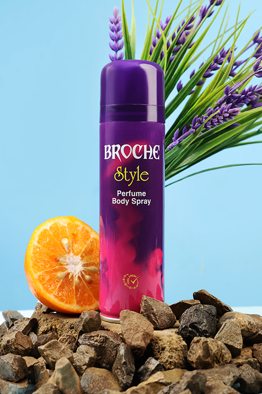 broche-body-spray-style-150ml-aluminum-bottle-on-rocks-with-orange-slice-and-flowers-in-the-background